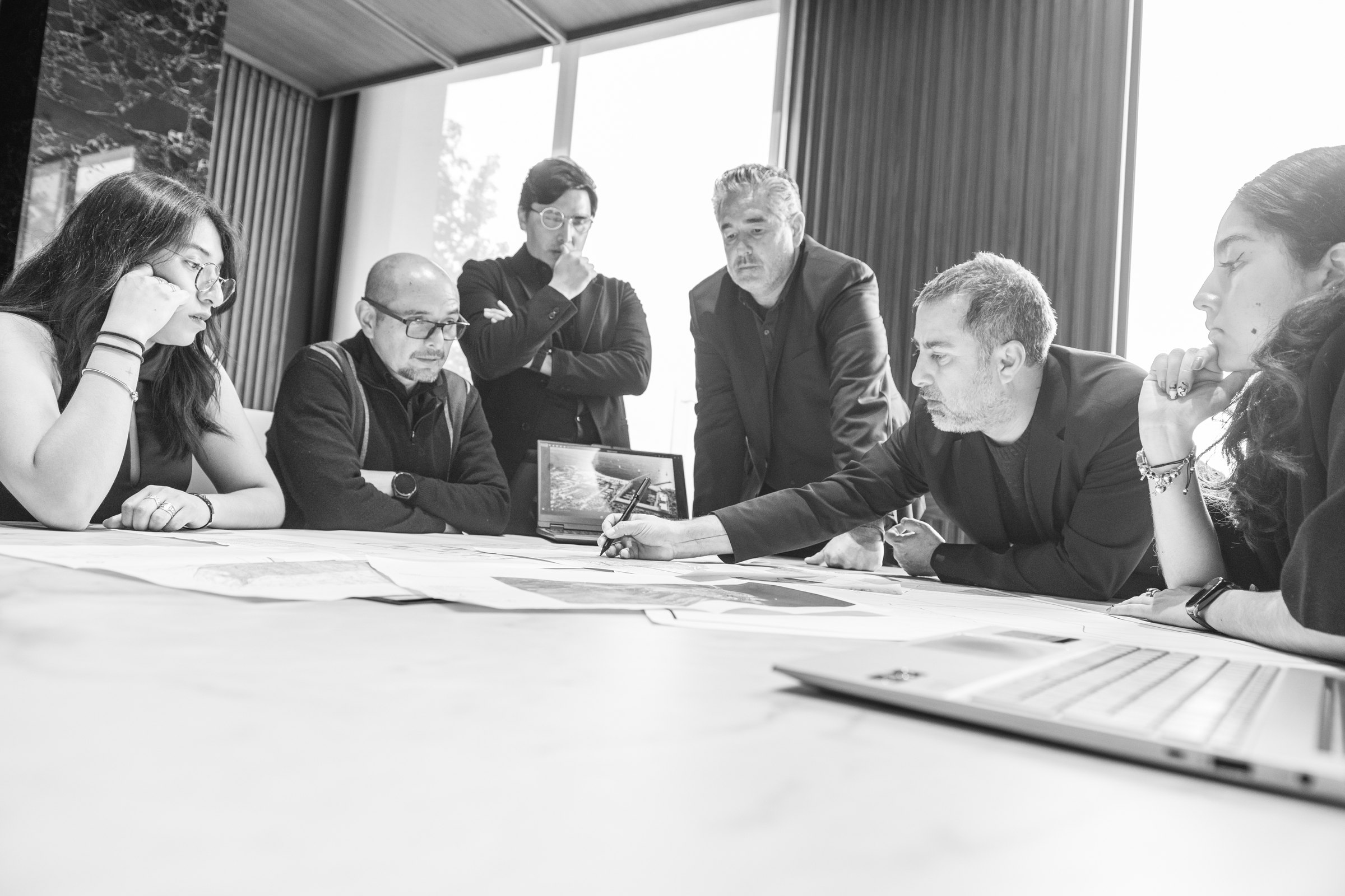 Seis integrantes del equipo de TRES alrededor de la mesa, revisando los planos de un proyecto