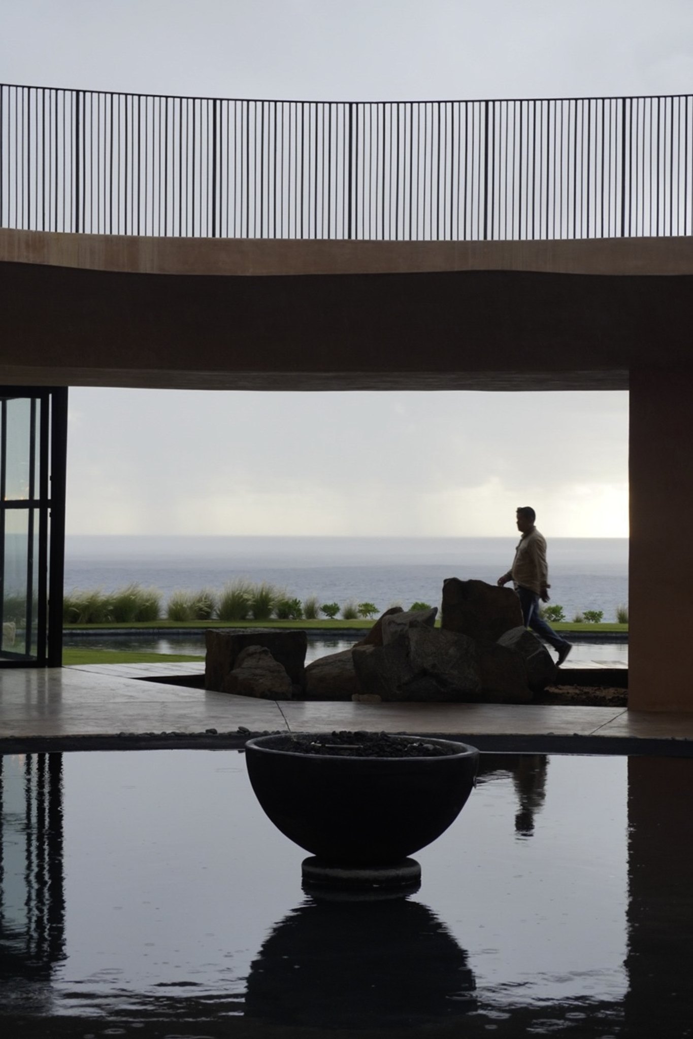 Estanque interior con una escultura, frente al ventanal al mar