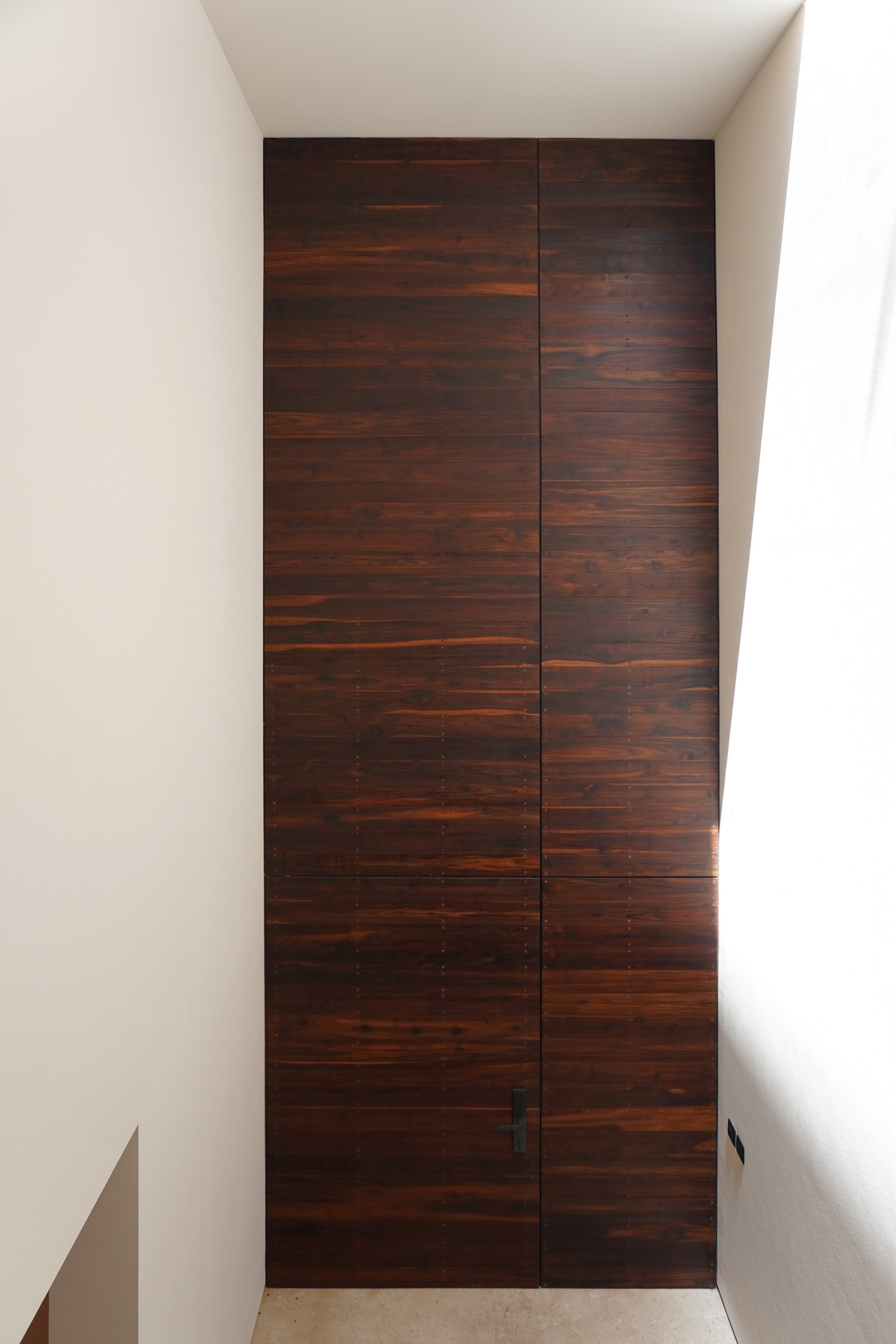 Puerta alta de madera sobre el muro blanco