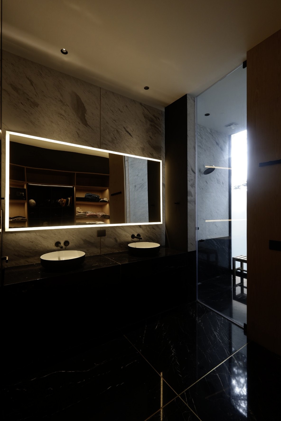 Baño con el espejo retroiluminado y el mármol oscuro